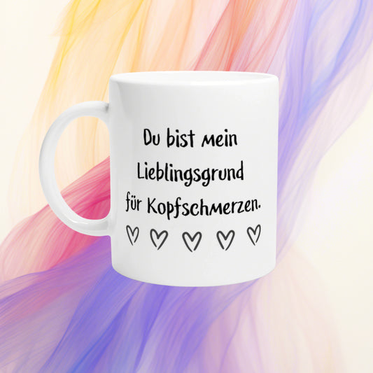 White mug mockup with the German phrase 'Du bist mein Lieblingsgrund für Kopfschmerzen' and a row of hearts on a colorful abstract background.