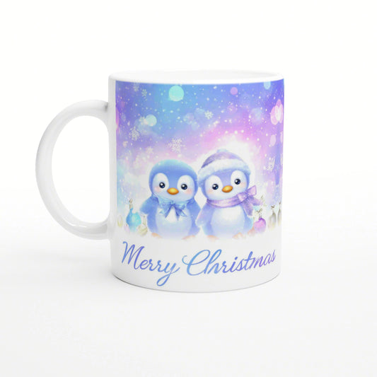 White mug with pastel winter scene, two penguins, snowflakes, ornaments, and Merry Christmas text.